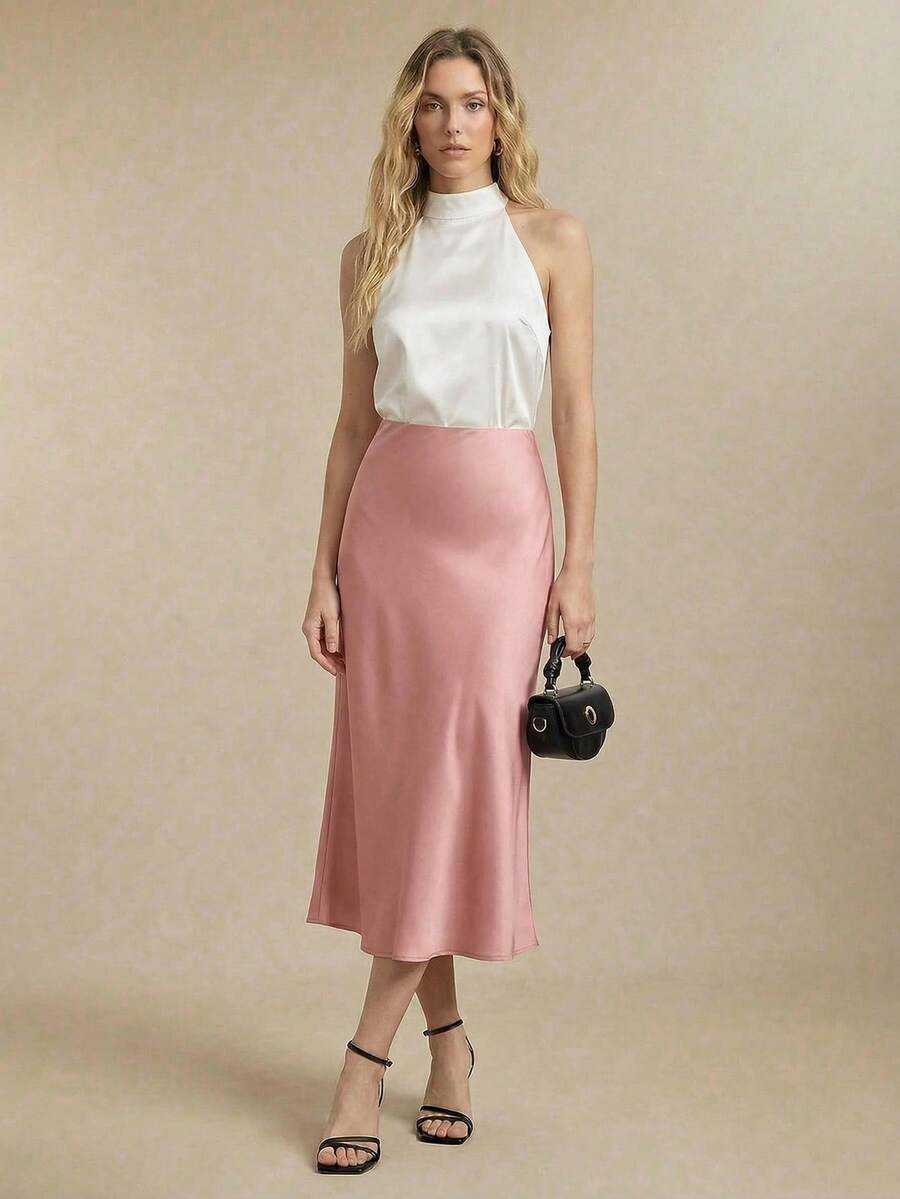 Modelo luciendo un conjunto de falda midi de satén rosa palo y top halter blanco.