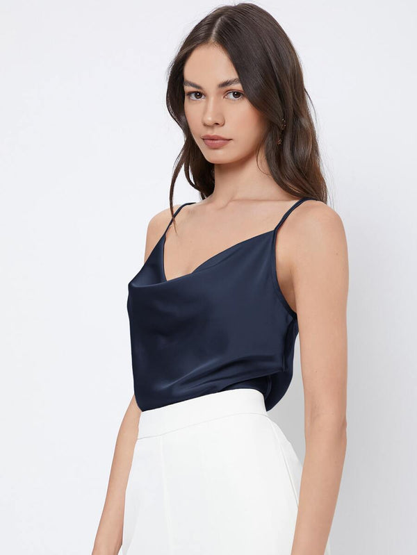 Silueta de un top satinado azul marino combinado con un pantalón de vestir blanco.