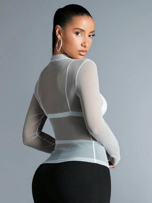 Mujer luciendo top blanco de malla transparente de espaldas.