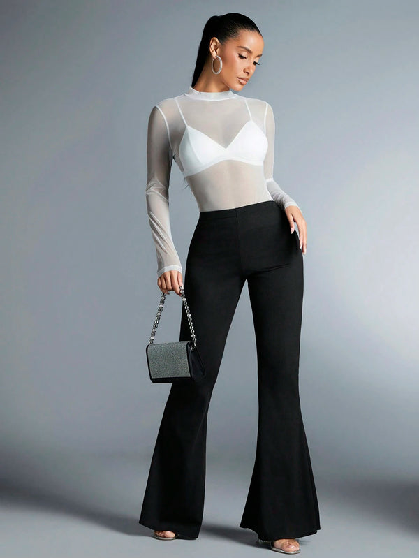 Top blanco de malla transparente combinado con pantalones negros acampanados.