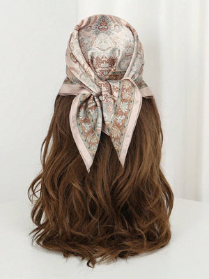 Detalle del pañuelo beige con estampado cayendo sobre la espalda de una mujer con una gabardina.