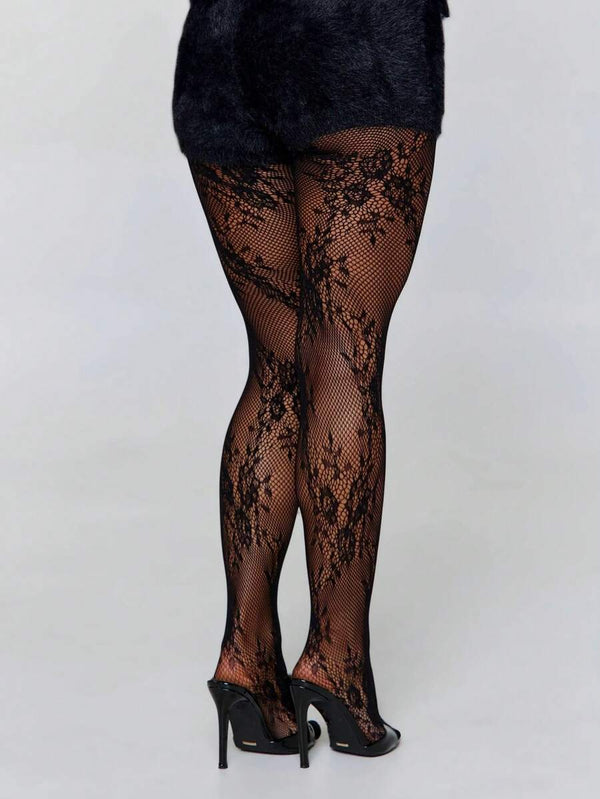 Detalle de los pies de una mujer con tacones negros de tiras y pantimedias de encaje floral.