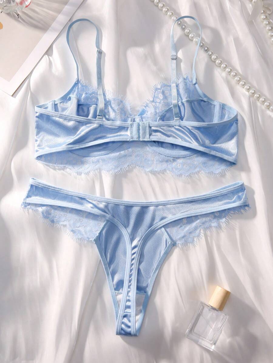 Conjunto de lencería azul cielo de satín y encaje sobre una tela blanca.