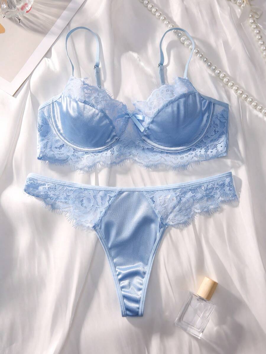 Conjunto de lencería azul cielo de satín y encaje sobre una tela blanca.