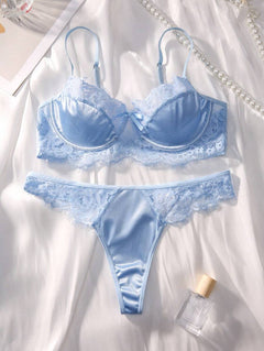 Conjunto de lencería azul cielo de satín y encaje sobre una tela blanca.