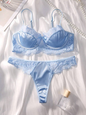 Conjunto de lencería azul cielo de satín y encaje sobre una tela blanca.