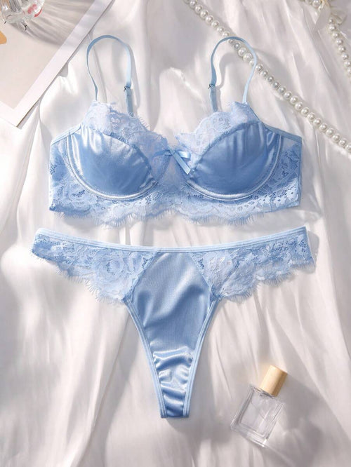 Conjunto de lencería azul cielo de satín y encaje sobre una tela blanca.