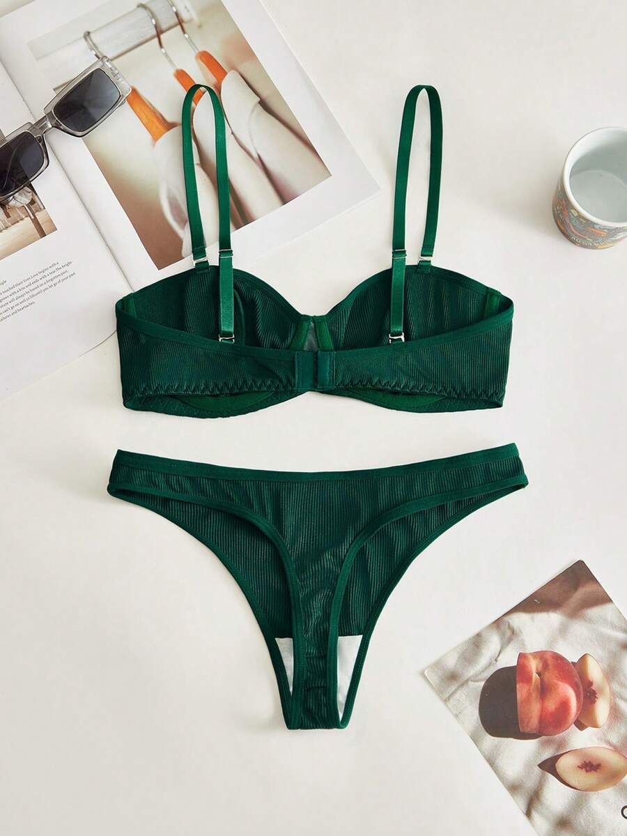 Conjunto de lencería acanalado verde oscuro sobre una superficie blanca.