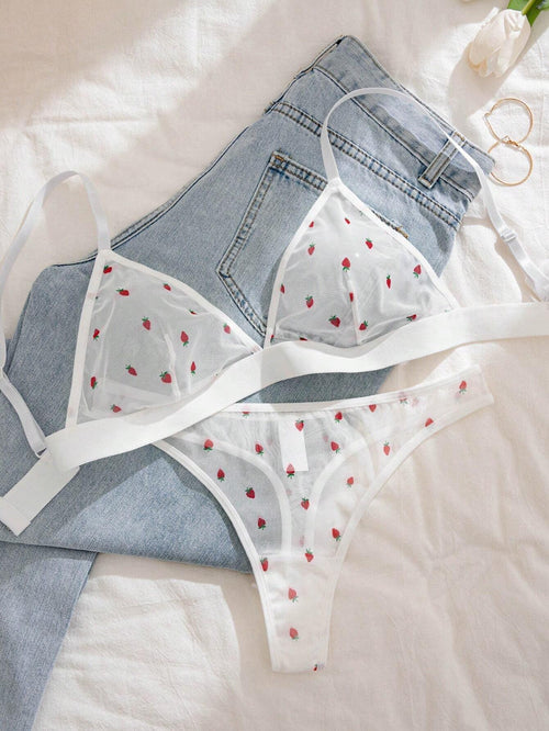 Set de lencería blanco con estampado de fresas sobre jeans - vista frontal.
