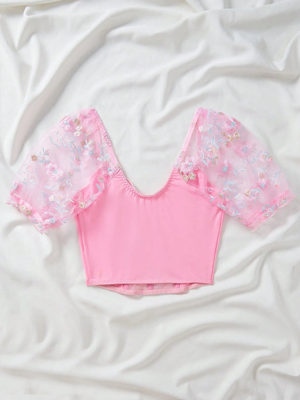 Modelo usando top romántico bordado rosado, vista frontal con detalles de bordado.
