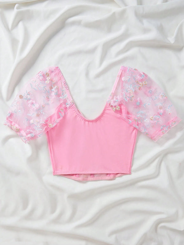 Vista trasera del top romántico bordado rosado con mangas transparentes.