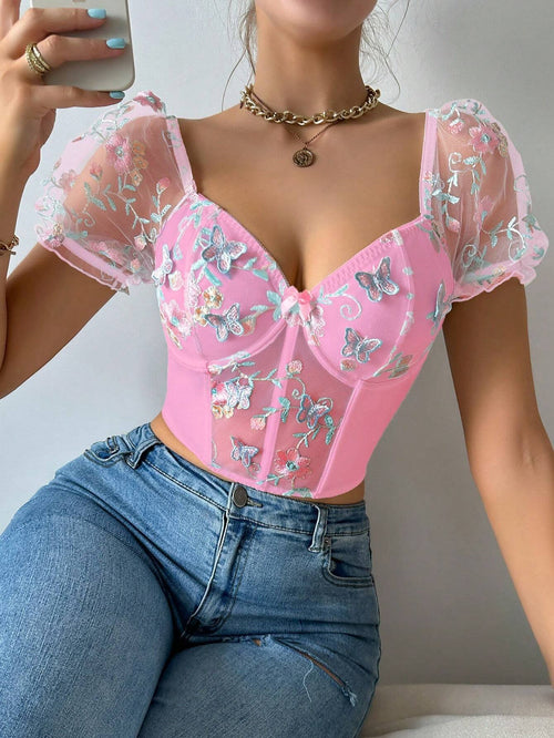 Modelo usando top romántico bordado rosado, vista frontal con detalles de bordado.