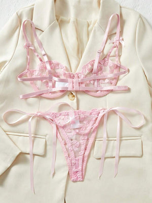 Conjunto sexy rosa con transparencias, detalle de tanga sobre fondo claro.