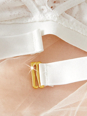 Broche metálico en sujetador de encaje blanco – acercamiento