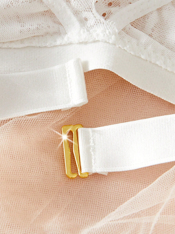 Broche metálico en sujetador de encaje blanco – acercamiento