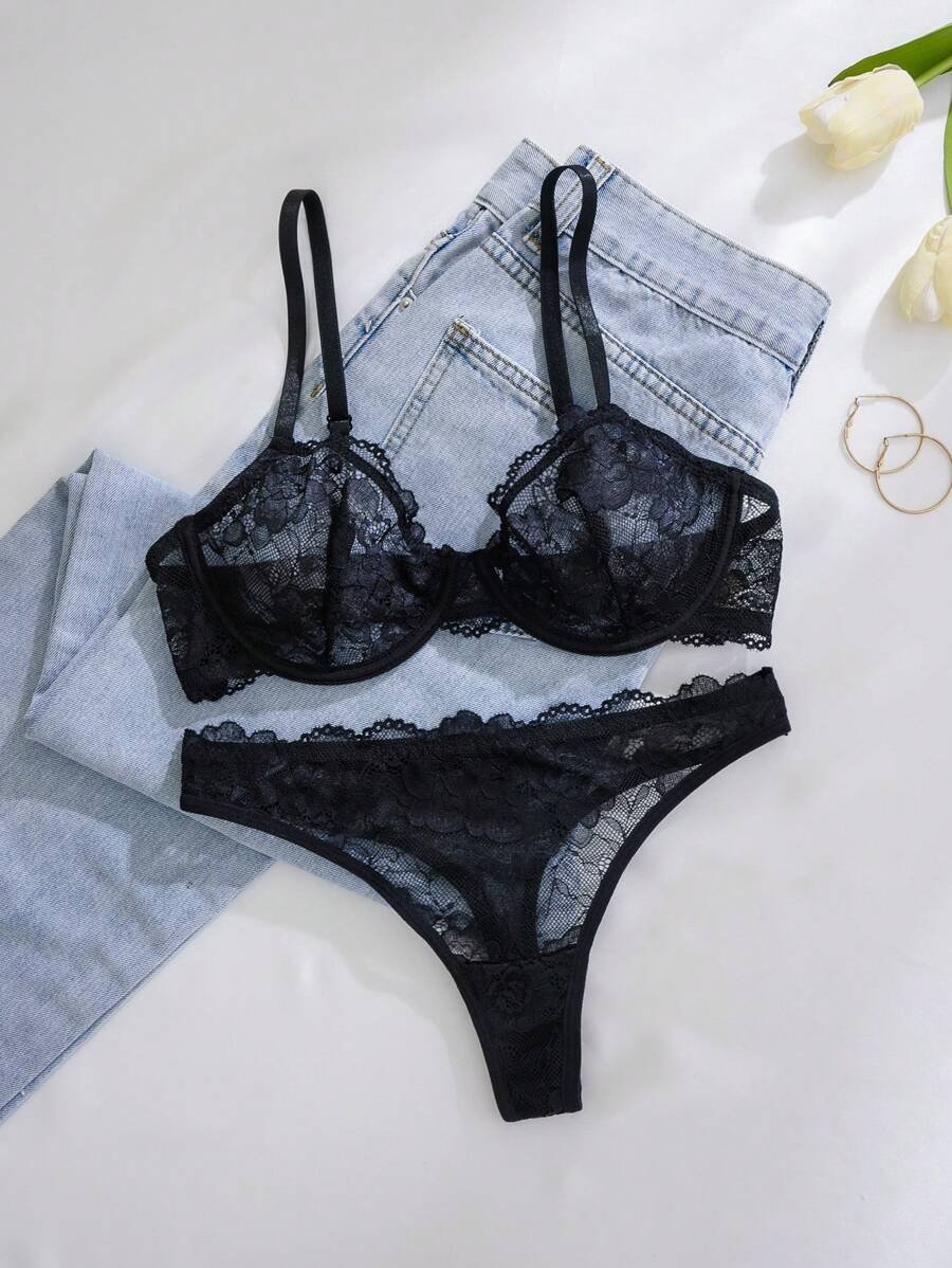 Set de lencería negro con encaje transparente sobre jeans claros.