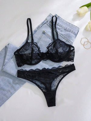 Set de lencería negro con encaje transparente sobre jeans claros.