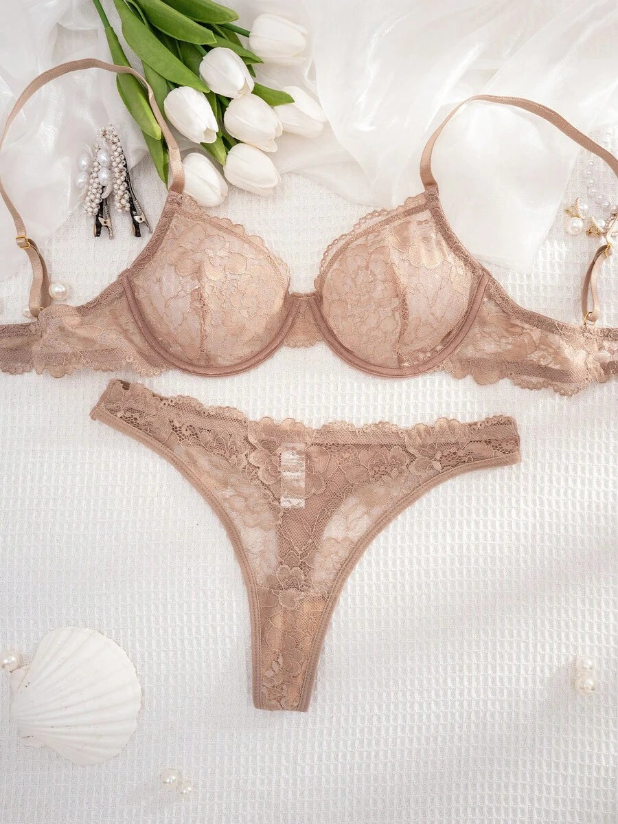 Conjunto de lencería de encaje floral color nude sobre una superficie blanca texturizada con flores.