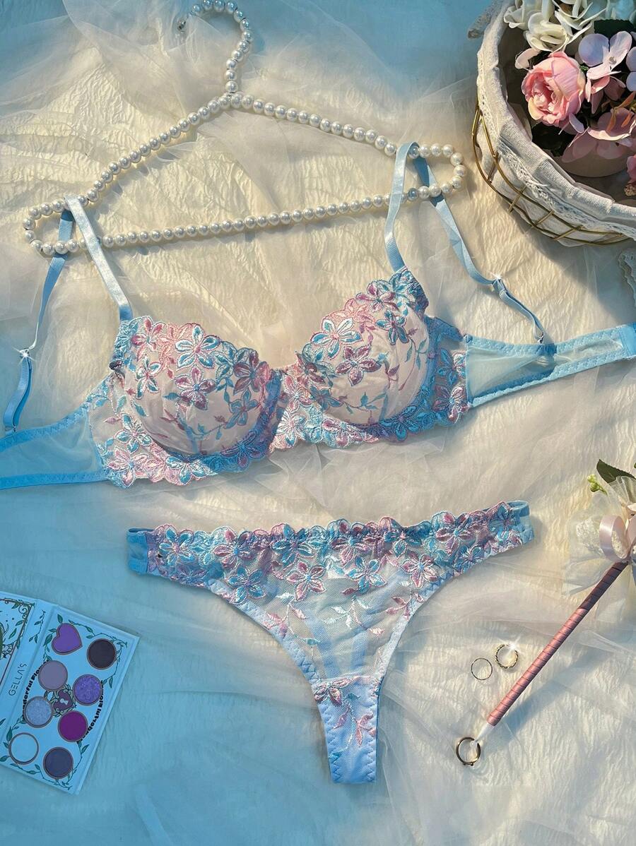 Conjunto de lencería con bordado floral en tonos celeste y rosa sobre un fondo de seda.