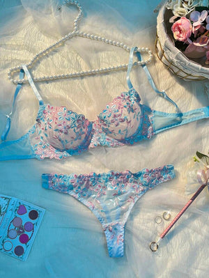 Conjunto de lencería con bordado floral en tonos celeste y rosa sobre un fondo de seda.