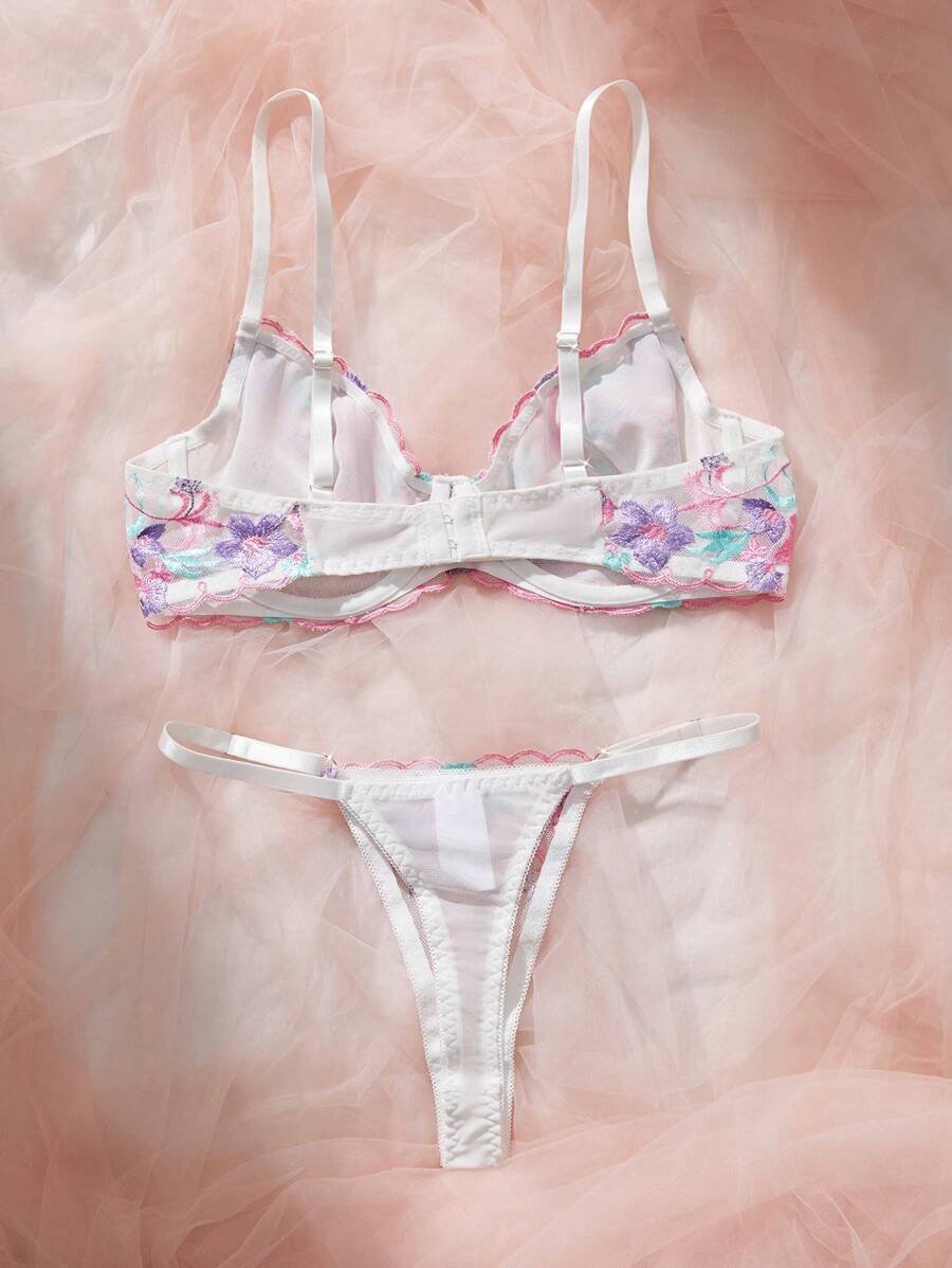 Set de lencería bordada multicolor con tanga y sujetador balconette sobre fondo rosa.