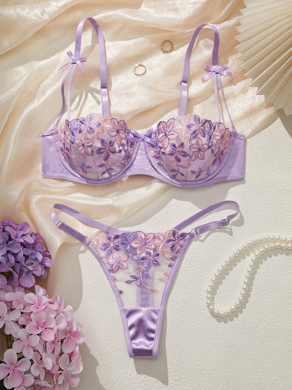 Imagen 1: Conjunto De Lencería Morada con bordado floral presentado sobre tela de seda.