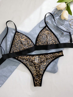 Conjunto de lencería con estampado de leopardo de dos piezas sobre una superficie blanca con unos jeans.