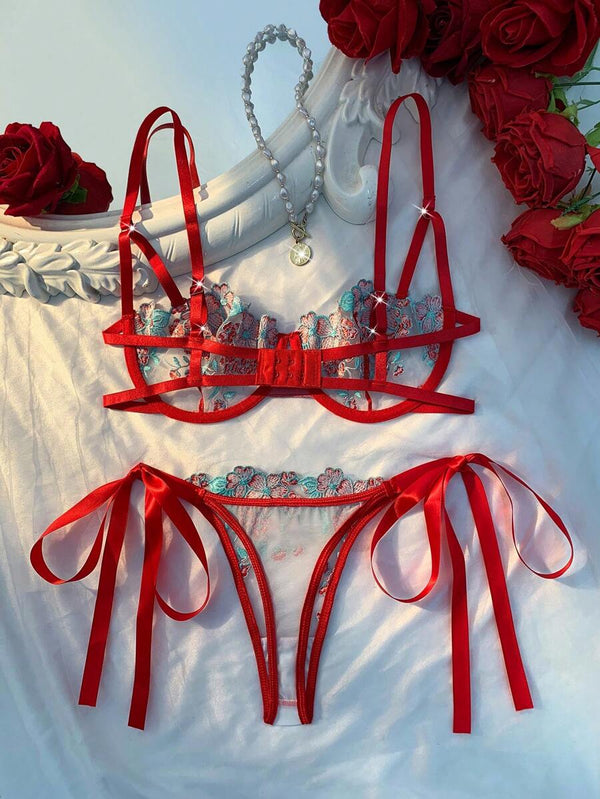 Detalle del sujetador de lencería con bordado floral y tirantes rojos ajustables.