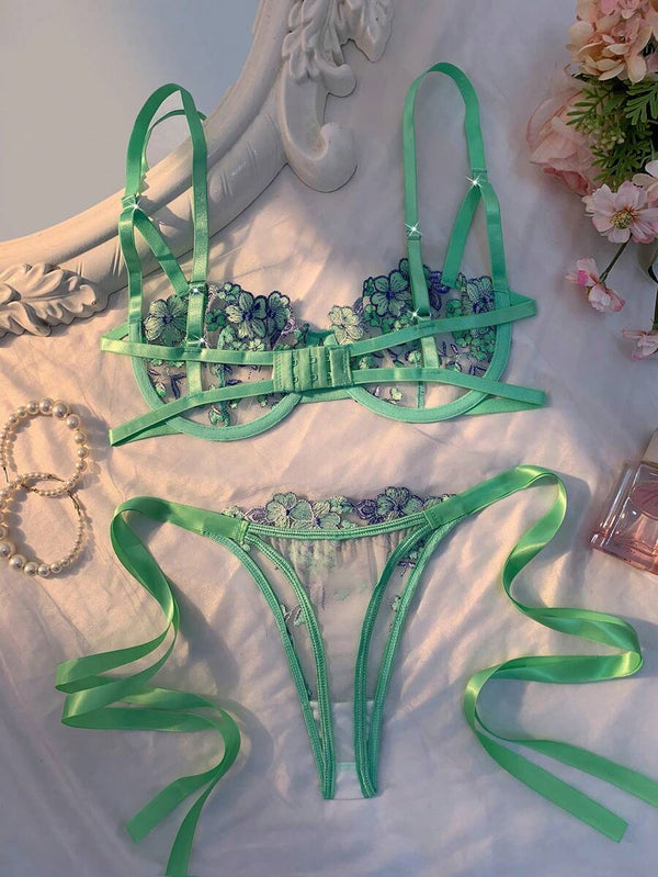 Detalle del sujetador de lencería verde menta con copas de malla transparente y bordado floral.