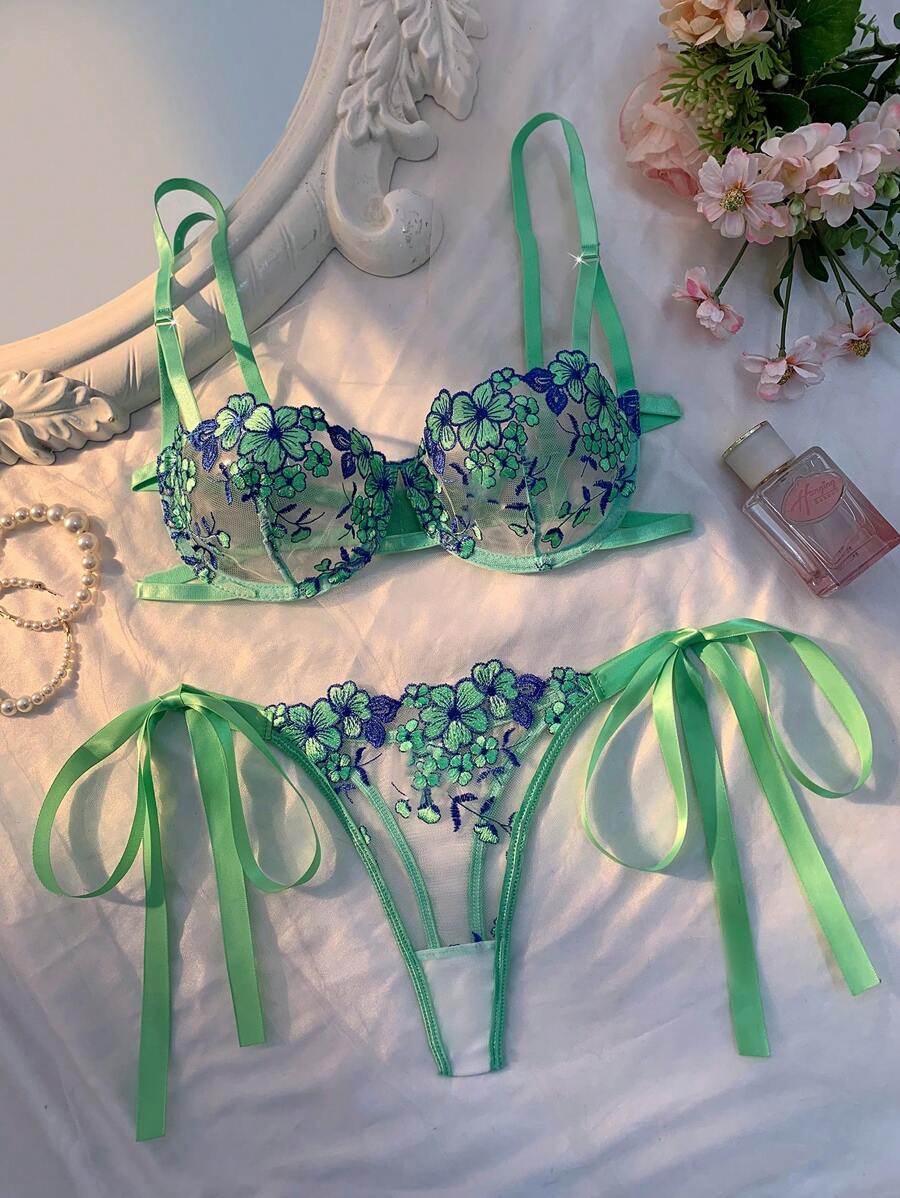 Conjunto de lencería verde menta con bordado floral azul y verde, sobre una superficie blanca.
