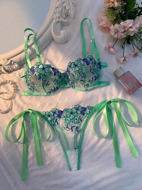 Conjunto de lencería verde menta con bordado floral azul y verde, sobre una superficie blanca.