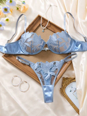 Conjunto de lencería azul cielo con bordado floral sobre un fondo de seda.