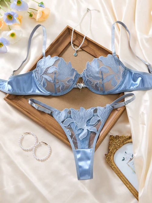 Conjunto de lencería azul cielo con bordado floral sobre un fondo de seda.