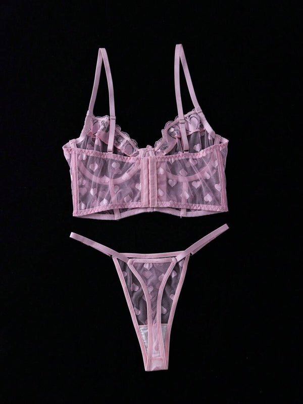 Vista detallada de la tanga de malla transparente rosa con corazones.