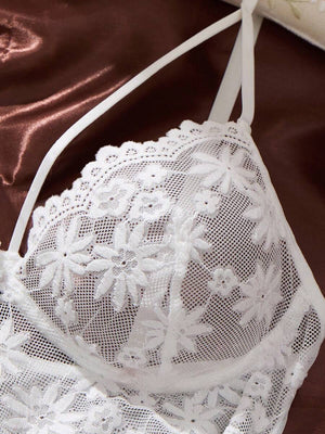 Detalle de la falda plisada y transparente del babydoll blanco junto a la tanga de encaje a juego.