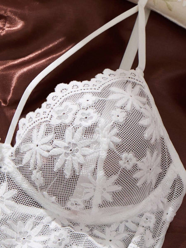 Detalle de la falda plisada y transparente del babydoll blanco junto a la tanga de encaje a juego.