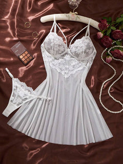 Conjunto de lencería babydoll blanco con encaje floral y tanga a juego sobre un fondo de satén marrón.