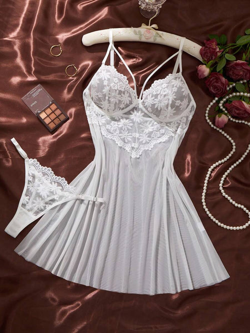 Conjunto de lencería babydoll blanco con encaje floral y tanga a juego sobre un fondo de satén marrón.
