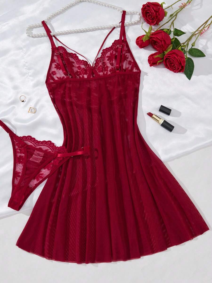 Conjunto de lencería rojo vino de encaje y malla sobre un fondo de seda blanca.