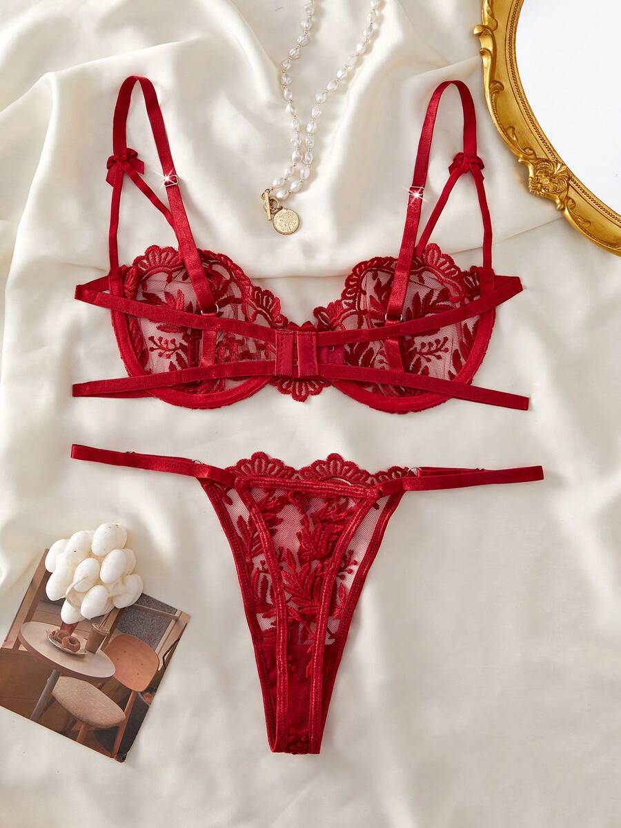 Conjunto de lencería rojo de dos piezas con bordado floral sobre un fondo de tela satinada.