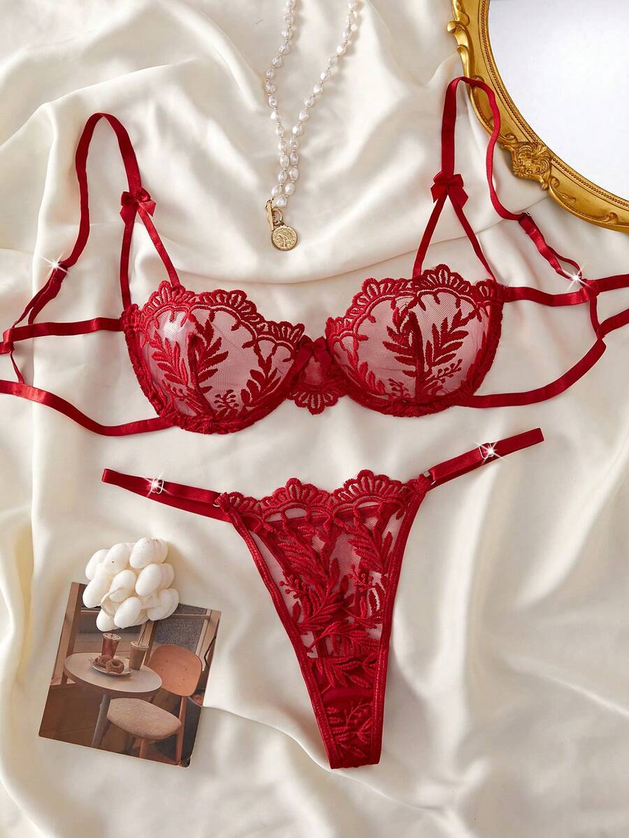 Conjunto de lencería rojo de dos piezas con bordado floral sobre un fondo de tela satinada.
