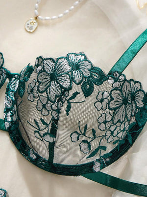 Primer plano del diseño floral bordado en la copa del sujetador de lencería verde esmeralda.