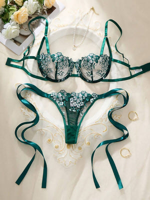 Conjunto de lencería verde esmeralda con bordado floral visto desde arriba sobre una superficie clara.