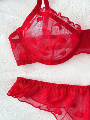 Vista superior de un conjunto de lencería rojo con estampado de corazones en tul y volantes.