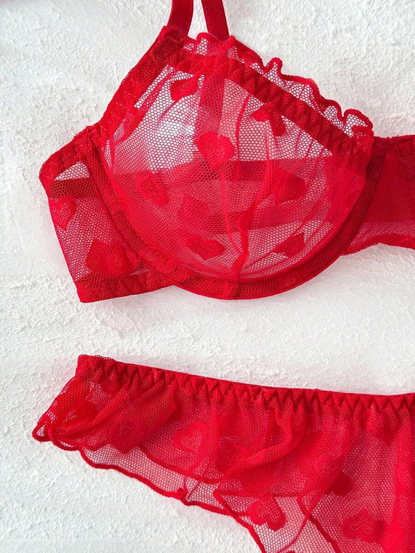 Vista superior de un conjunto de lencería rojo con estampado de corazones en tul y volantes.