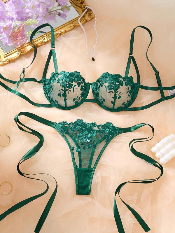 Detalle de la tanga de lencería verde esmeralda con lazos de satén laterales.