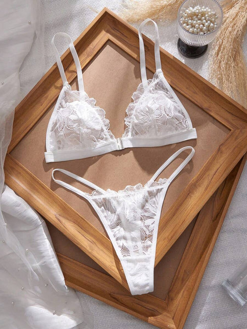Conjunto de lencería de encaje blanco con bralette triangular y tanga, visto desde arriba.