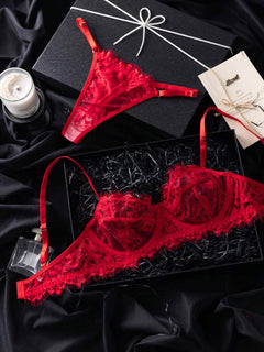 Conjunto de lencería de encaje rojo con sujetador y tanga sobre un fondo negro satinado.