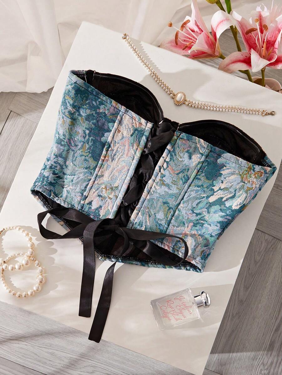 Top corsé floral estilo tapiz en tonos azules y verdes sobre una superficie blanca.