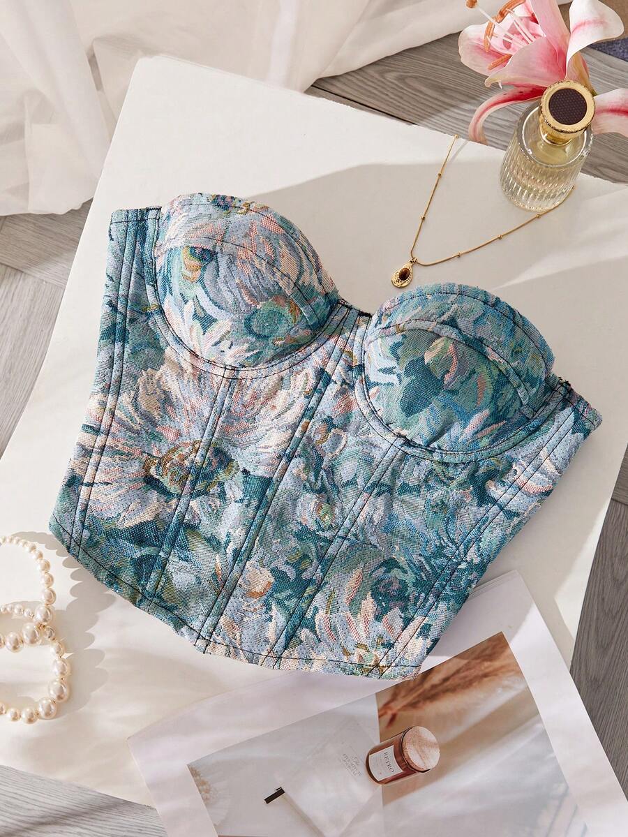 Top corsé floral estilo tapiz en tonos azules y verdes sobre una superficie blanca.